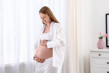 Evde karnı dokunmadan güzel hamile kadın