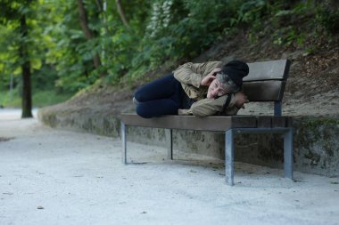 Evsiz adam parkta bankta yatıyor, mesaj için yer var.