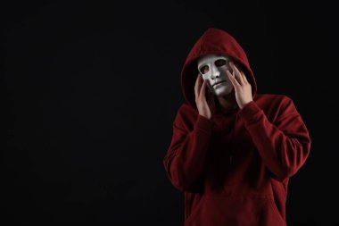 Anonimlik. Koyu arkaplanda maske takan adam, metin için boşluk