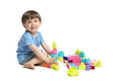 Beyaz arka planda tuğlalarla oynayan sevimli küçük çocuk.