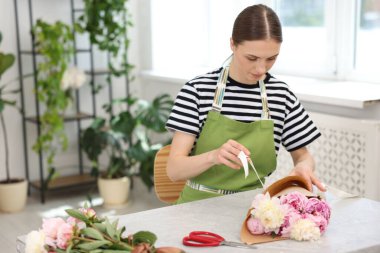 Çiçekçi çiçekçide şakayık buketi yapıyor, mesaj için yer var.