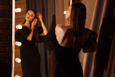 Güzel bir kadın aynanın yanında hazırlanıyor.