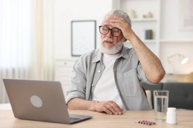 Üst düzey bir adam kapalı bir masada dizüstü bilgisayarla doktorla görüşüyor.