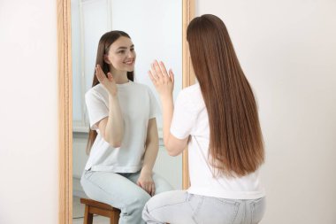 Güzel bir kadın aynada kendine bakıyor.