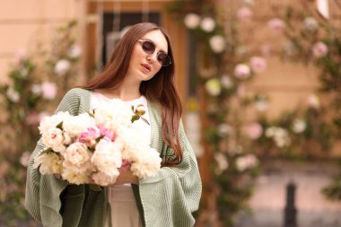 Şehir caddesinde bir buket güzel şakayığı olan çekici bir kadın. Metin için boşluk