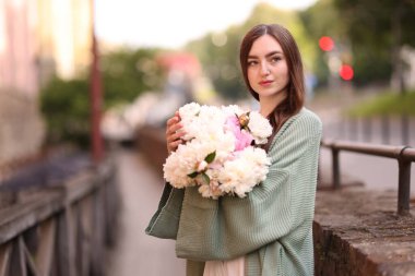 Şehir caddesinde bir buket güzel şakayığı olan çekici bir kadın. Metin için boşluk