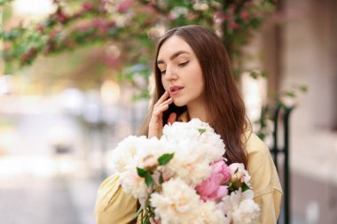 Şehir caddesinde elinde şakayık demeti olan bir kadın. Metin için boşluk