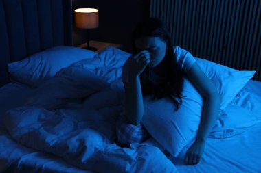 Evde yatağında uykusuzluk çeken, yastıklı hayal kırıklığına uğramış bir kadın.