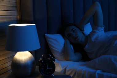 Evde yatakta uykusuzluk çeken hayal kırıklığına uğramış bir kadın.