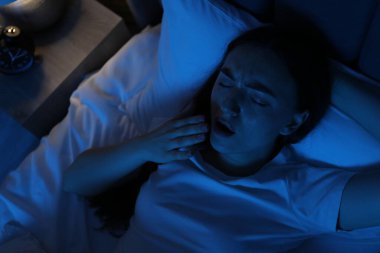 Evdeki yatakta uykusuzluk çeken hayal kırıklığına uğramış bir kadın.