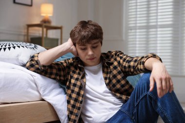 Gençlik sorunları. Evde yerde yatan üzgün genç çocuk.