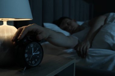 Evde uykusuzluk çeken sinirli adam, alarmlı saate odaklan.