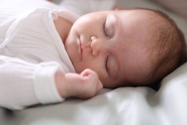 Sevimli yeni doğmuş bebek yatakta uyuyor, yakın plan.