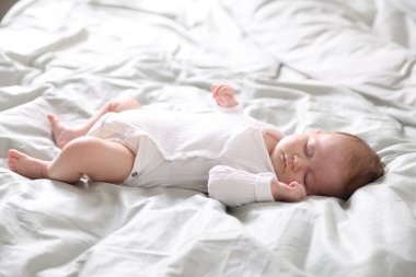 Tatlı tatlı yeni doğmuş bebek yatakta uyuyor.