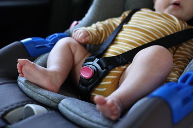 Sevimli küçük bebek araba koltuğuna bağlanmış, yakın plan.