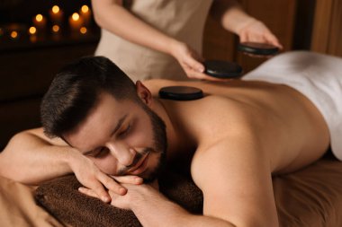 Adam spa salonunda taşlarla masaj yaptırıyor.