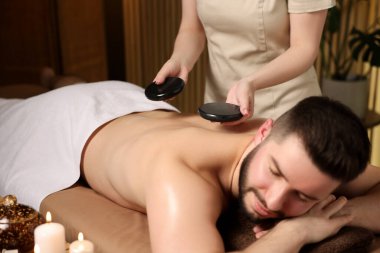 Adam spa salonunda taşlarla masaj yaptırıyor.