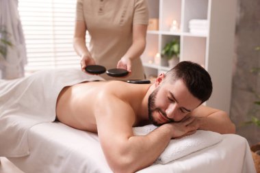 Adam spa salonunda taşlarla masaj yaptırıyor.