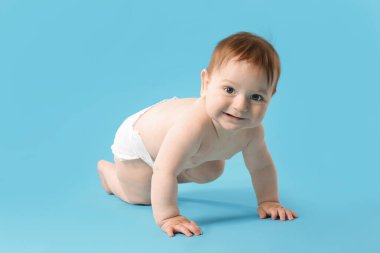 Açık mavi arka planda emekleyen şirin bir bebek.