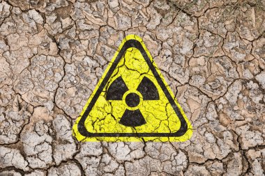 Çatlak kuru toprak üzerindeki sarı radyoaktif tabela, üst manzara. Radyolojik kirlilik