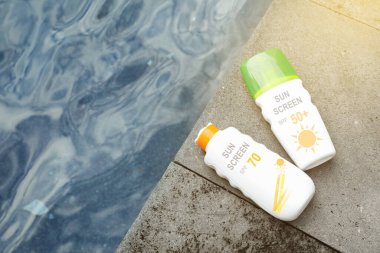 Güneş kremleri deniz kenarındaki taş yüzeyde, üst tarafta. Güneş koruma ürünü