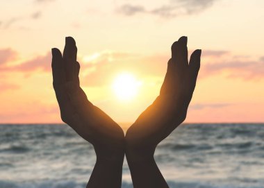 Umut. Gökyüzüne karşı bulutlarla ve güneşle el ele tutuşan kadın, yaklaş.