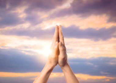 Umut. Dua eden ve elele tutuşan kadın bulutlar ve güneş ile, yakın çekim