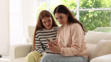 Anne ve genç kızı evde selfie çekiyorlar.