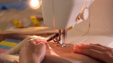 Atölyede dikiş makinesi ve kumaşla çalışan bir kadın.