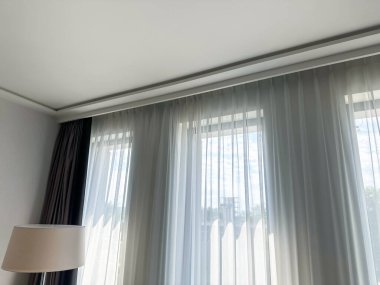 Güzel perdeler pencerenin yanında asılı, alçak açılı manzara.