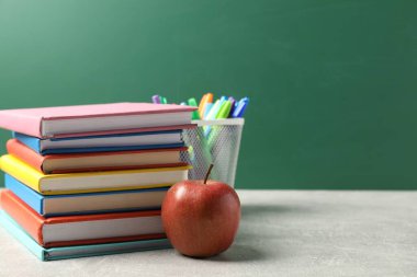 Farklı okul kırtasiyesi ve gri masada kırmızı elma karatahtaya karşı, metin için yer