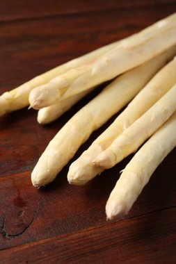 Ahşap masada bir sürü çiğ kuşkonmaz mızrağı var. Yakın plan.