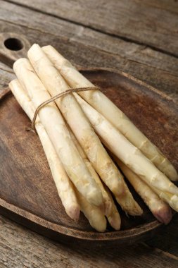 Ahşap masada çiğ beyaz kuşkonmaz mızrakları, yakın plan.