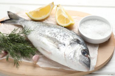 Beyaz ahşap masadaki baharatlı taze çiğ dourade, yakın plan. Balık ve deniz ürünleri lezzetleri