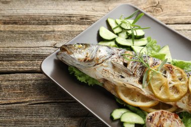 Ahşap masada sebze ve limonla servis edilen kızarmış deniz kabuğu balığı, yakın plan. Ev yapımı deniz ürünleri yemeği.