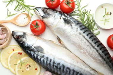 Taze çiğ uskumrular ve baharatlar beyaz masada, düz yerde. Deniz ürünleri lezzetleri.