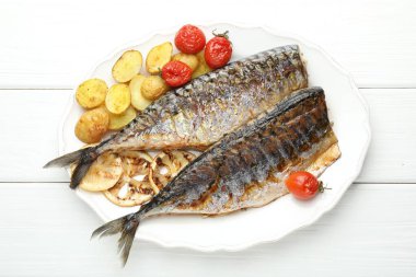 Lezzetli kızarmış uskumrular, limonlu, domatesli ve patatesli beyaz ahşap masa, üst manzara. Ev yapımı deniz ürünleri yemeği.