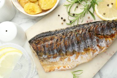 Beyaz mermer masada baharatlı ve patatesli kızarmış uskumru. Ev yapımı deniz ürünleri yemeği.