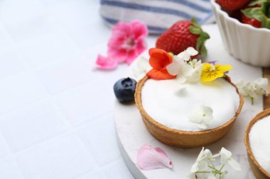 Lezzetli tatlı. Kremalı tart, çilek ve çiçekli beyaz fayanslı masa, yakın plan. Metin için boşluk