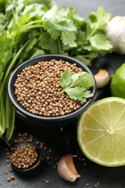 Koyu dokulu masada kişniş tohumları taze kişniş, kireç ve sarımsak, yakın plan.