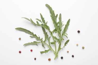 Taze yeşil roka yaprakları ve beyaz arka planda biberler, düz yatıyordu.