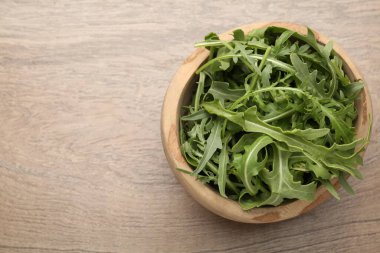 Tahta masadaki kasede taze yeşil roka yaprakları, üst manzara. Metin için boşluk