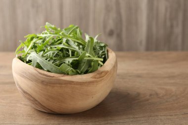 Tahta masadaki kasede taze yeşil roka yaprakları, yakın plan. Metin için boşluk