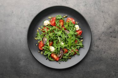 Lezzetli salata roka, mozzarella ve gri masada sebzeler.