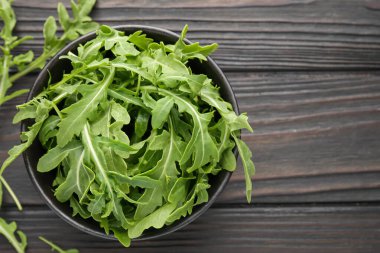 Taze yeşil roka yaprakları koyu ahşap masa üzerinde, üst manzara. Metin için boşluk