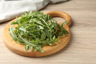 Taze yeşil roka yaprakları açık ahşap masada, yakın plan.