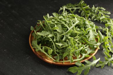 Taze yeşil roka yaprakları siyah masada, yakın plan.