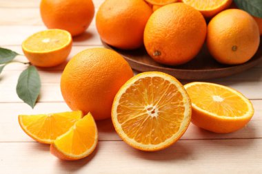 Taze portakallar ve yapraklar açık ahşap masada, yakın plan.