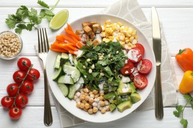 Beyaz ahşap masada servis edilen farklı sağlıklı vejetaryen yemekleri.