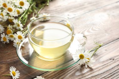 Lezzetli papatya çayı ve çiçekler ahşap masada, yakın plan. Metin için boşluk